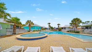 A pool area with lounge chairs, palm trees, and houses in the background. - Welcome to Drift & Tide Cottage, your quiet coastal escape in Fort Morgan. (Gulf Shores)