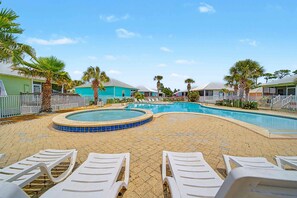 A pool area with lounge chairs, palm trees, and houses in the background. - Welcome to Drift & Tide Cottage, your quiet coastal escape in Fort Morgan. (Gulf Shores)