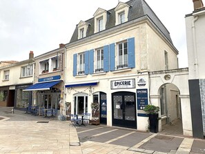 Ein Gebäude mit einer blauen Markise mit dem Schriftzug 'LE CASIER' und einer schwarzen Tür mit der Beschriftung 'ÉPICERIE'.