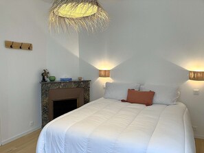 A bedroom with a bed, a fireplace, wall-mounted lamps, and a ceiling light fixture. - Voile - Saint Gilles Croix de Vie (SAINT GILLES CROIX DE VIE)