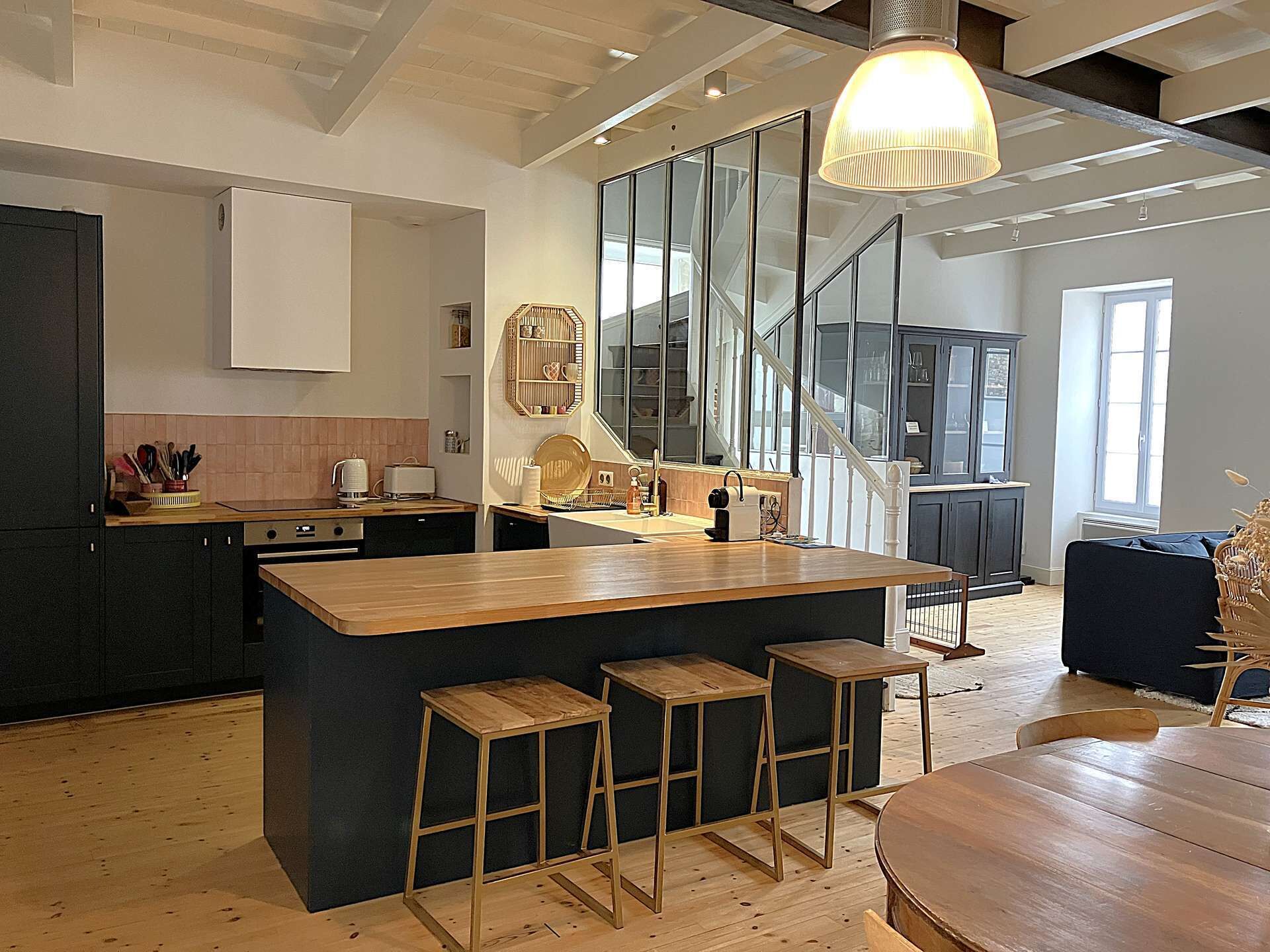 Une cuisine moderne dotée d’un îlot central, de tabourets de bar et d’un escalier menant à un niveau supérieur.