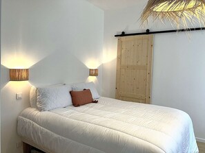 Ein Bett mit weißer Bettwäsche, zwei Wandlampen und ein Holzschrank.