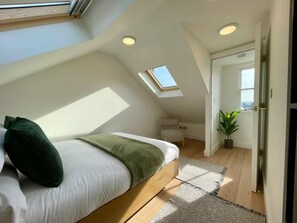 A bedroom with a skylight, a bed, a small table, and a potted plant. - Canterbury Stay Modern Duplex 2 min to Station (Canterbury)