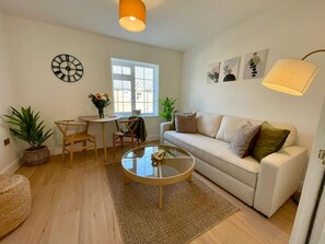 A living room with a sofa, coffee table, and a dining area with chairs and a table. - Canterbury Stay Modern Duplex 2 min to Station (Canterbury)