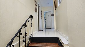 A narrow hallway with a wooden staircase and a black metal railing. - Hip Strip Vibe (Montego Bay)
