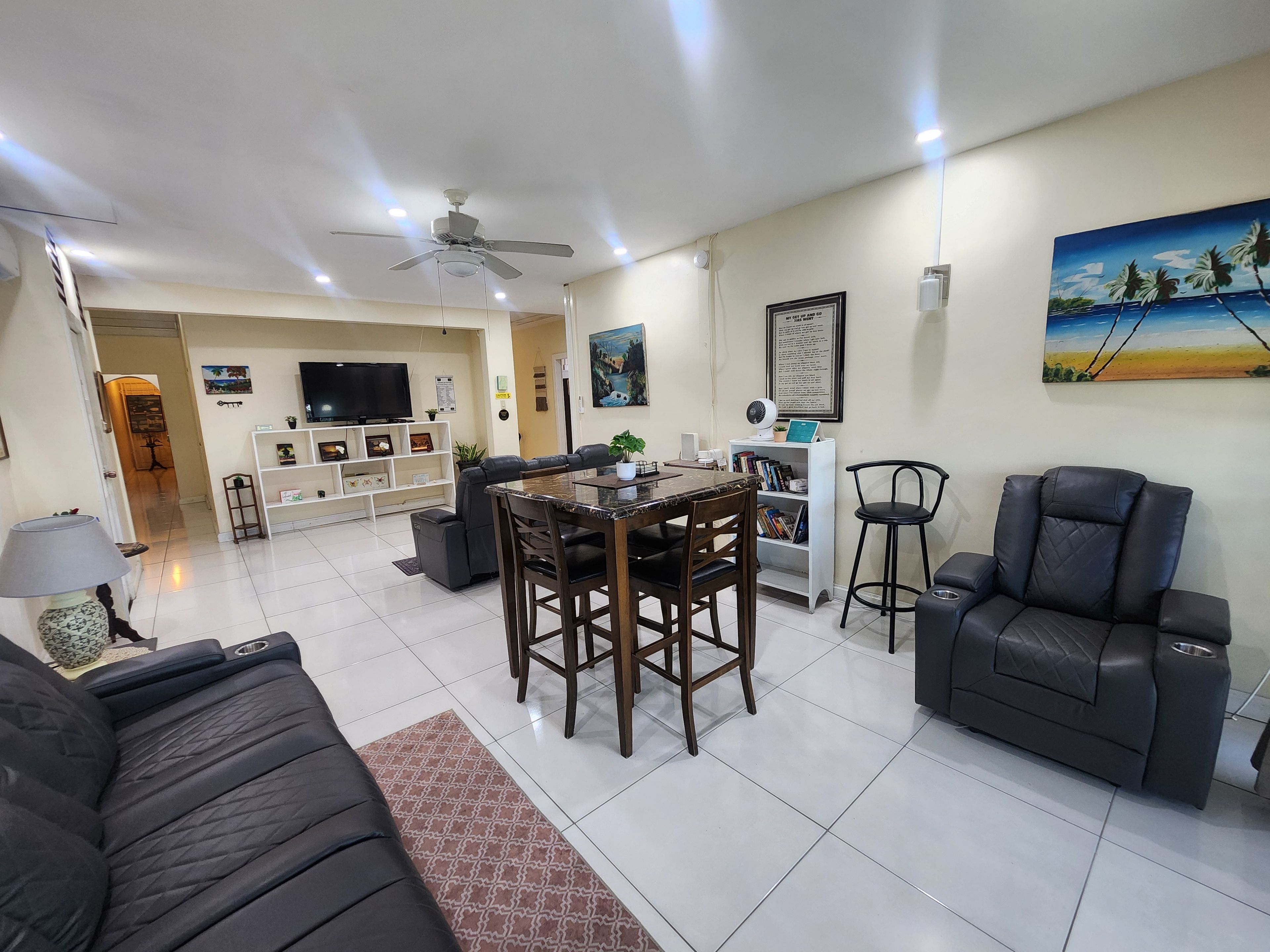 A modern living room with a dining area, a black leather sofa, a coffee table, and a TV.