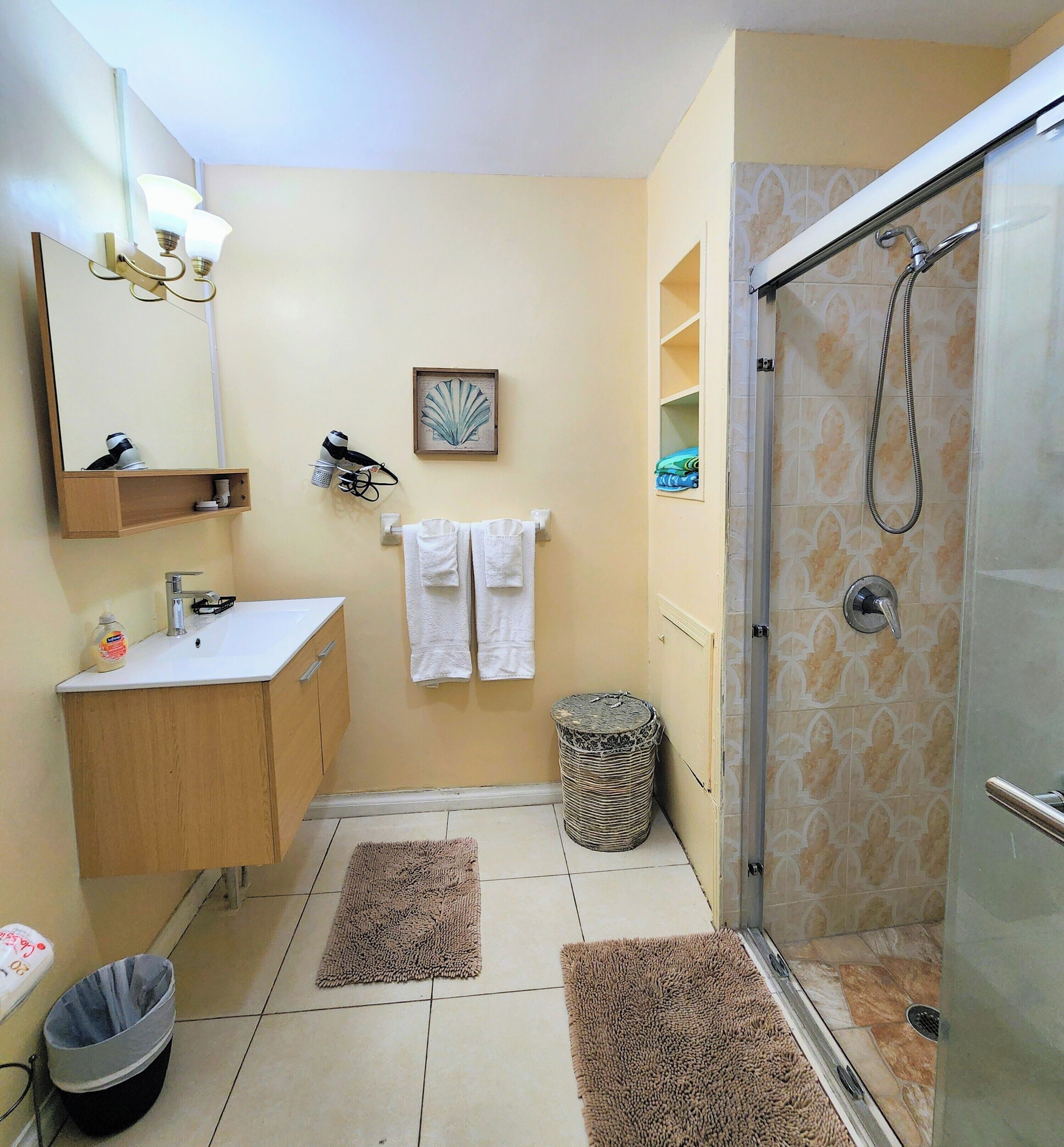 A bathroom with a shower, sink, and towel rack.