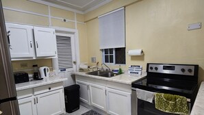 A kitchen with white cabinets, a black stove, a sink, and patterned floor tiles. - Hip Strip Vibe (Montego Bay)
