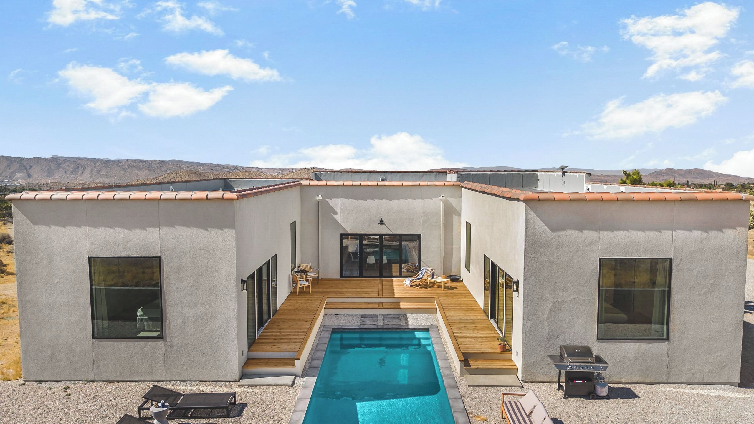 A modern house with a swimming pool, large windows, and a patio area.