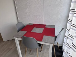 Ein kleiner Essbereich mit einem Tisch, vier Stühlen und einer roten und grauen Tischmatte.