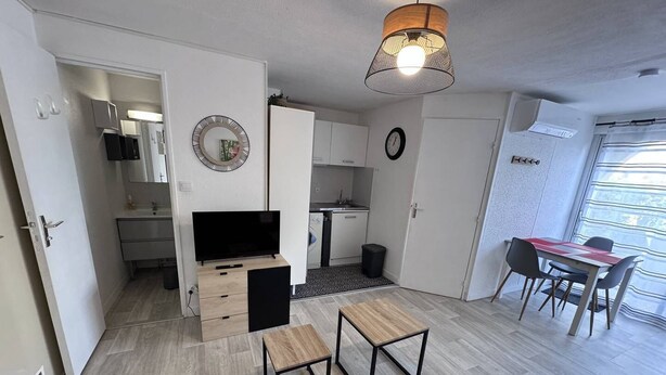 Un espacio habitable compacto con kitchenette, comedor y televisor.