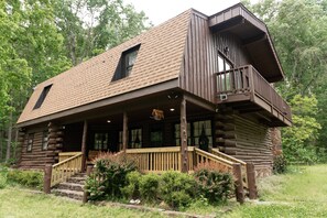 Eine Blockhütte mit Balkon, Holzstufen und Veranda.