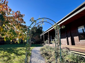 Un sentier de jardin mène à un bâtiment en bois doté d’un porche abrité.