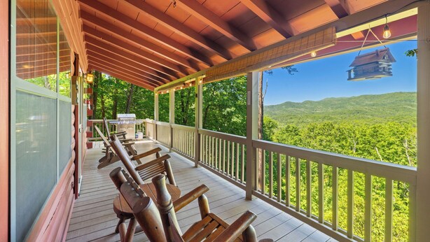 Una terraza de madera con bancos, barandilla y vista a un paisaje boscoso.