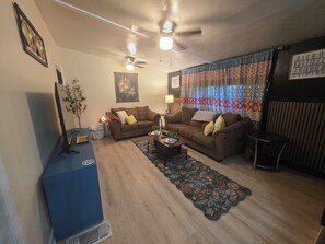 A living room with two couches, a coffee table, a TV, and a patterned curtain.