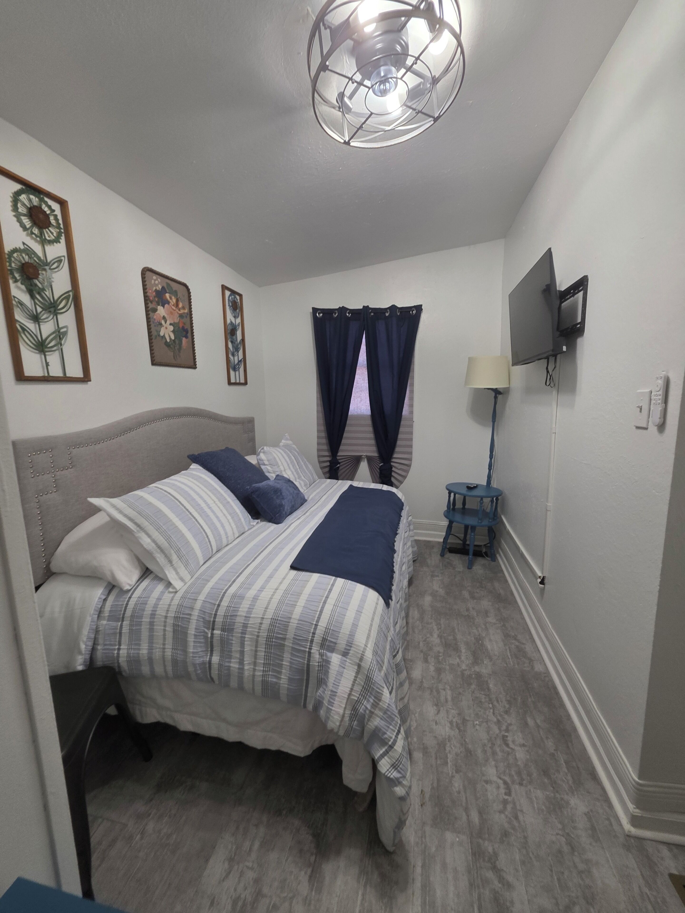 A bedroom with a bed, a TV, a lamp, and a small table.
