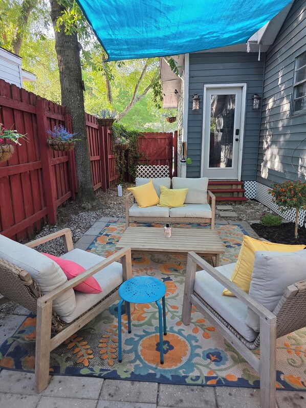 A patio with a wooden table, two sofas, and a small round table.