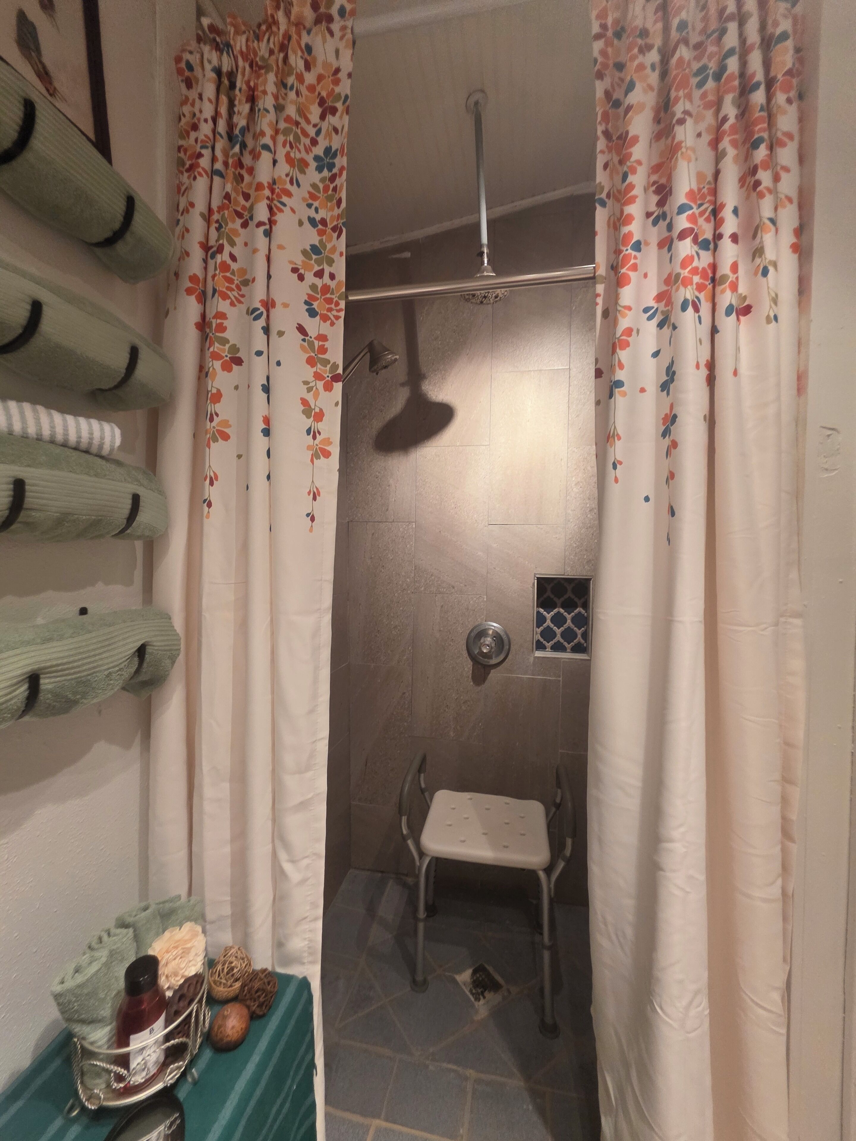 A shower area with a showerhead, a small window, and a stool.