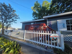 A house with a red staircase, a white picket fence, and a welcome sign.