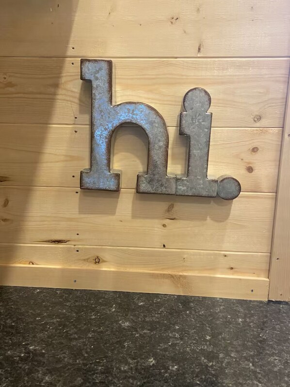 A wooden wall with a metal sign spelling 'hi.' - The Denali Cabin w/ Queen Bed (Seward)