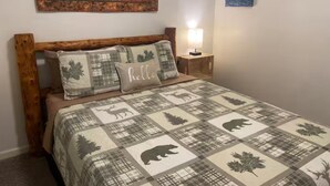 Ein Bett mit einer Bettdecke mit Tiermustern, einem hölzernen Kopfteil und einer Wand mit gerahmten Kunstwerken.