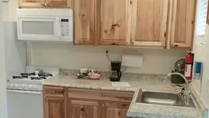 Eine Küche mit Holzausstattung, einem weißen Herd, einer Kaffeemaschine und einem Spülbecken.