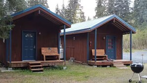 Two wooden cabins with front porches, each with a bench and a door. - The Kodiak Cabin w/ King Bed (Seward)