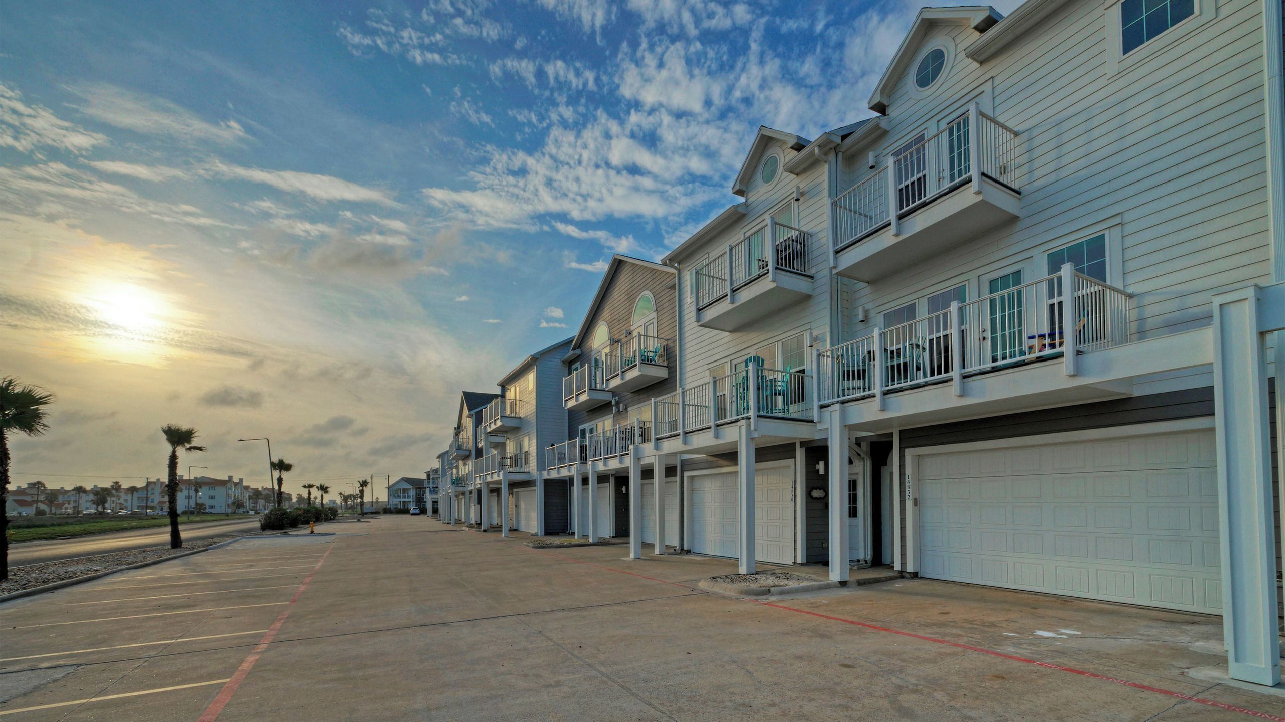 A row of townhouses with attached garages, a clear sky, and a sunset.