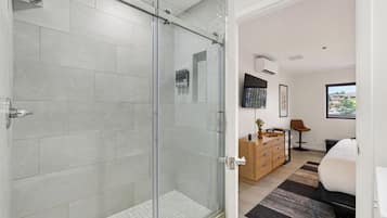 A modern bathroom with a glass shower enclosure, a wooden vanity, and a view of the outdoors through a window.