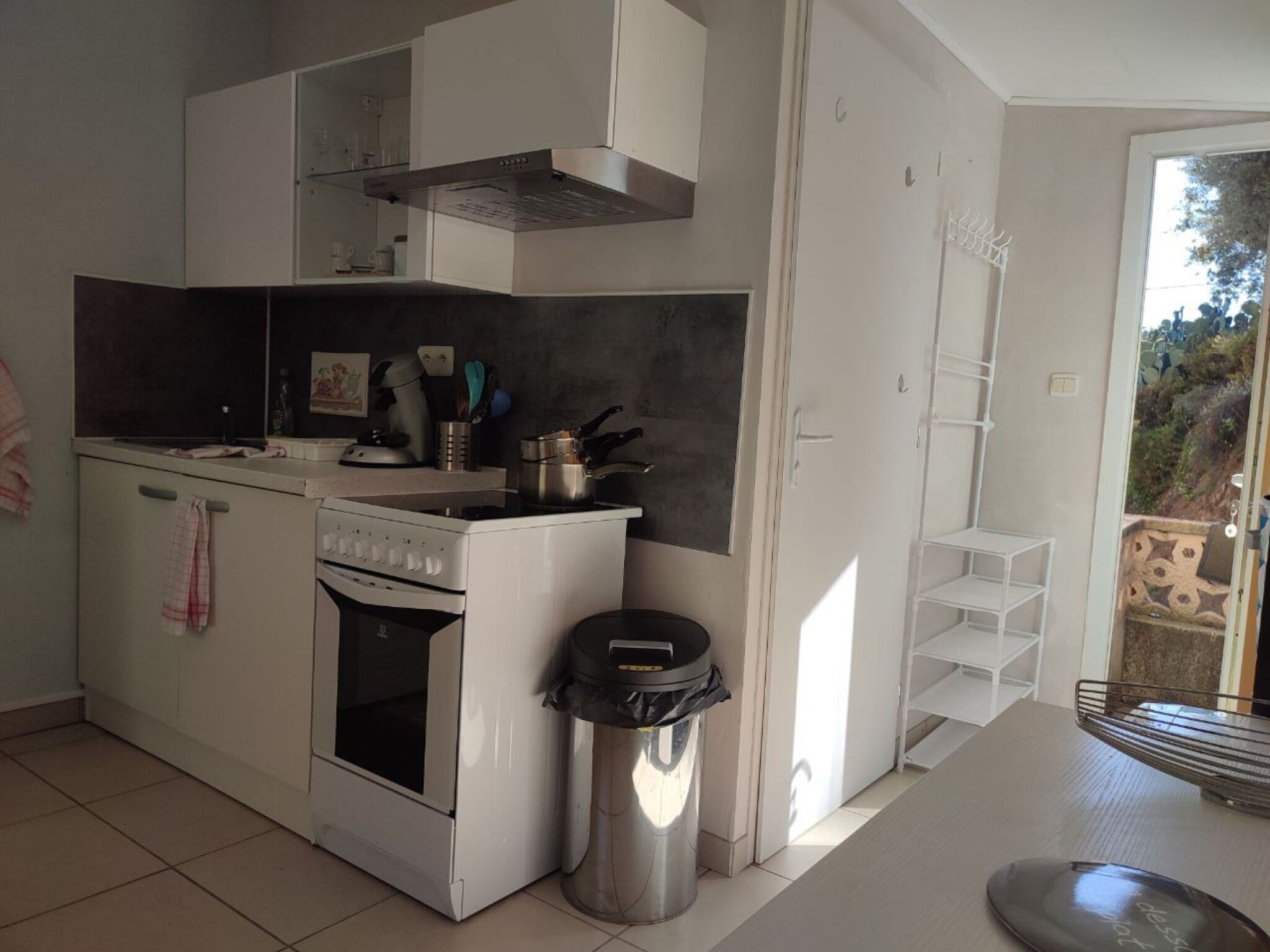 A compact kitchen with a stove, oven, and a trash bin.