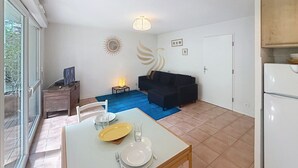 Un espace de vie compact comprenant un coin repas, un canapé, une petite table et un réfrigérateur.