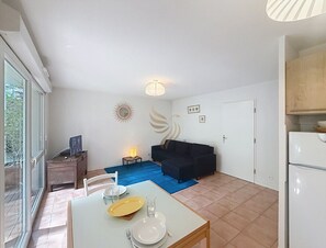 Ein kompakter Wohnbereich mit Essplatz, einer Couch, einem kleinen Tisch und einem Kühlschrank.
