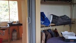 A room with a bed, a TV, a window, a kitchen area with a stove, and a gas cylinder. - New room aere and casita wifi pedasi/venao panama (El Ciruelo)