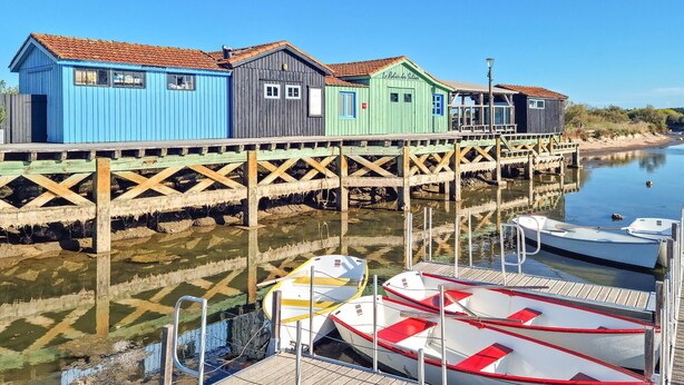 A waterfront with colorful wooden buildings and boats docked. - Charmante maison proche plage (Saint-Georges-d'Oléron)