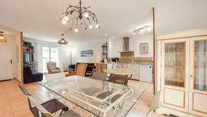 A modern kitchen with a dining table, chairs, and a chandelier. - Charmante maison proche plage (Saint-Georges-d'Oléron)
