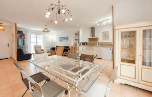 A modern kitchen with a dining table, chairs, and a chandelier. - Charmante maison proche plage (Saint-Georges-d'Oléron)