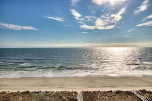 Ein Strand mit blauem Himmel, Wellen und einem Weg zum Wasser.