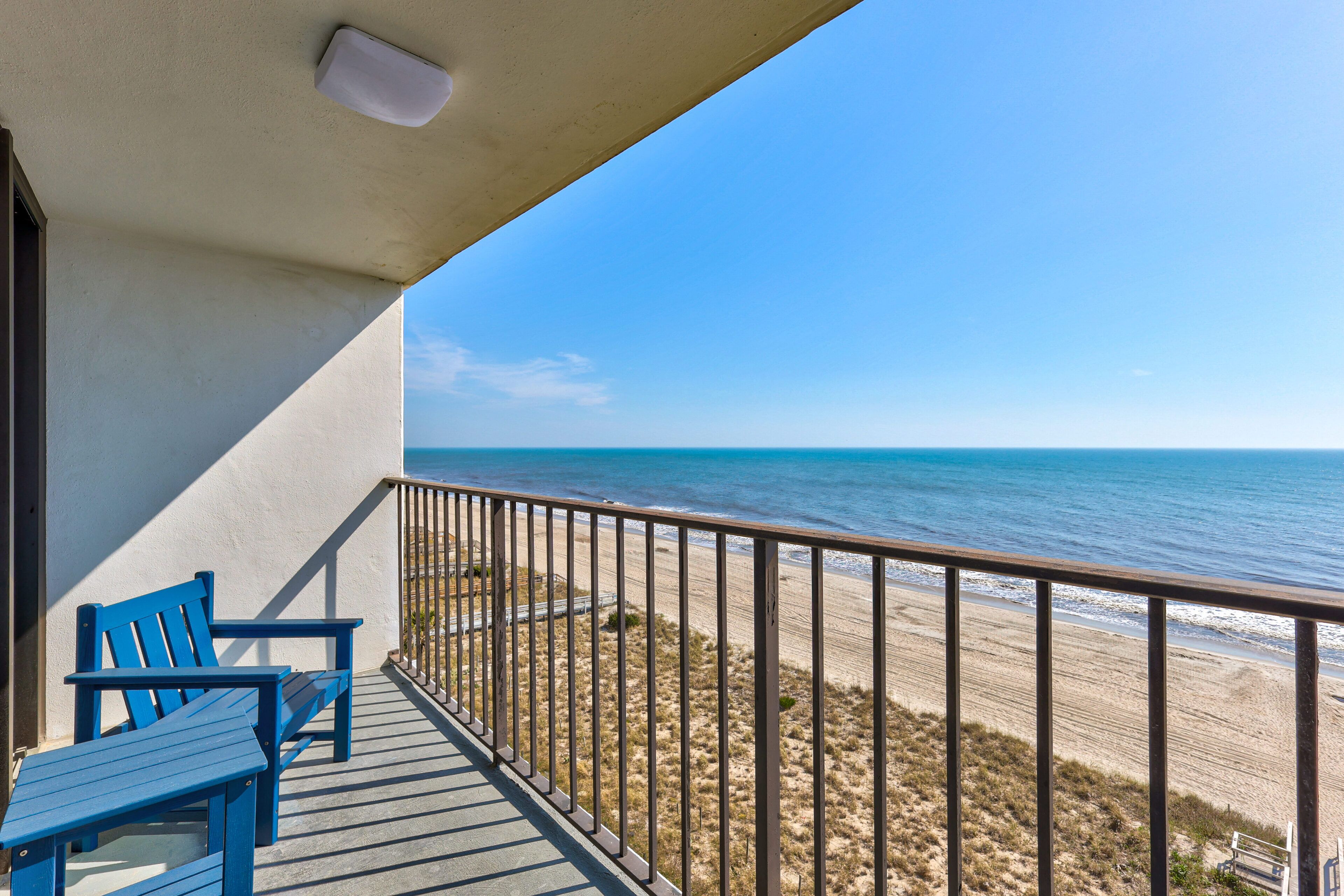 A balcony with a view of the beach and ocean.
