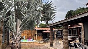 Un patio con palmeras, una piscina, asientos al aire libre y un edificio con techo de tejas.