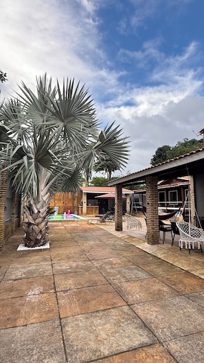 A courtyard with palm trees, a pool, outdoor seating, and a building with a tiled roof.