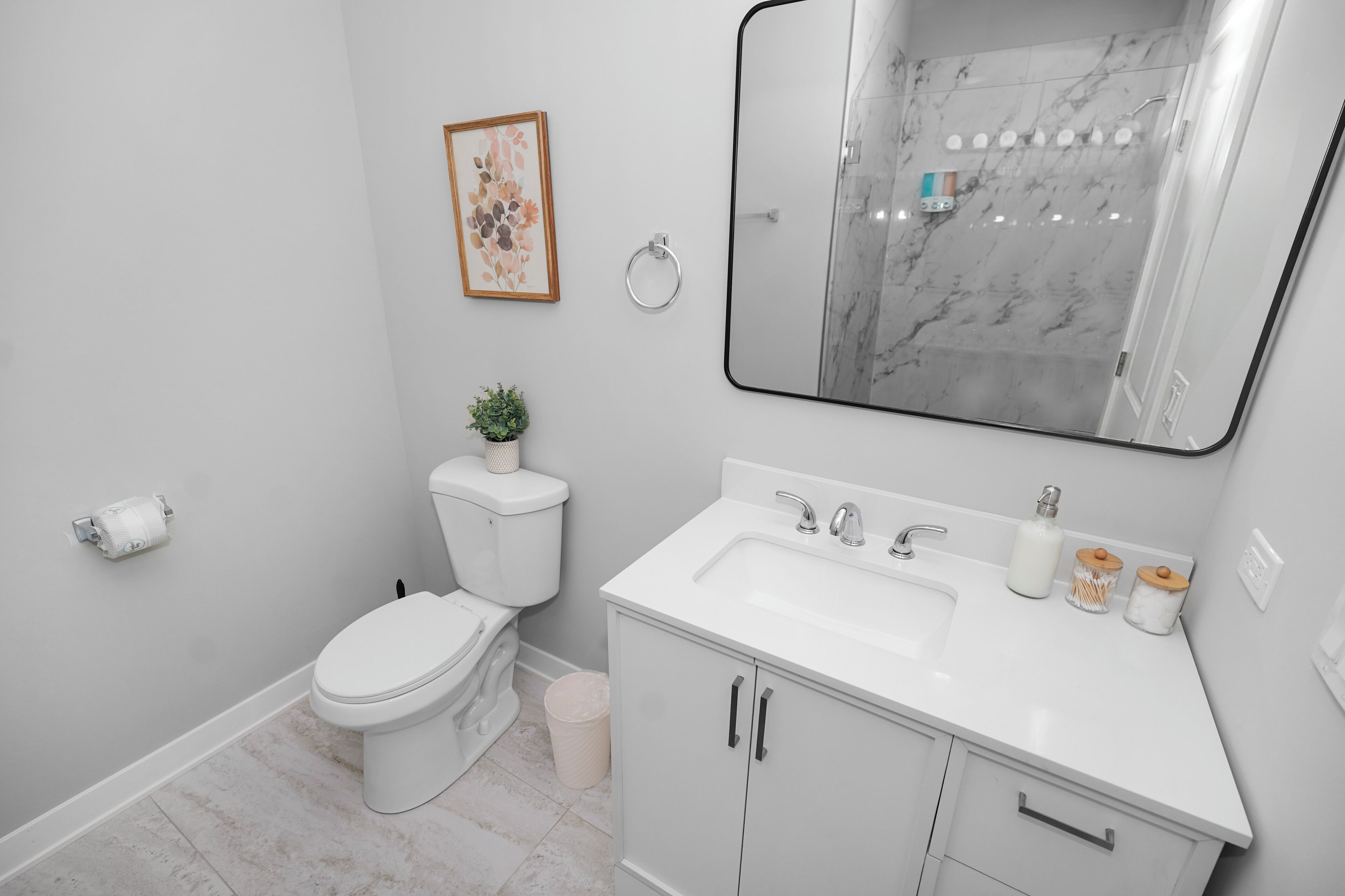 Ein modernes Badezimmer mit Toilette, Waschbecken, Spiegel und Marmorfliesen.