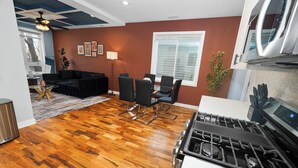 A modern kitchen with a gas stove, dining area with chairs, and a living room with a sofa and coffee table. - Urban Chicago 3BR Retreat, 5 min to West Loop (Chicago)