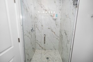 A glass-enclosed shower with a marble wall, a shower control panel, and a drain. - Urban Chicago 3BR Retreat, 5 min to West Loop (Chicago)