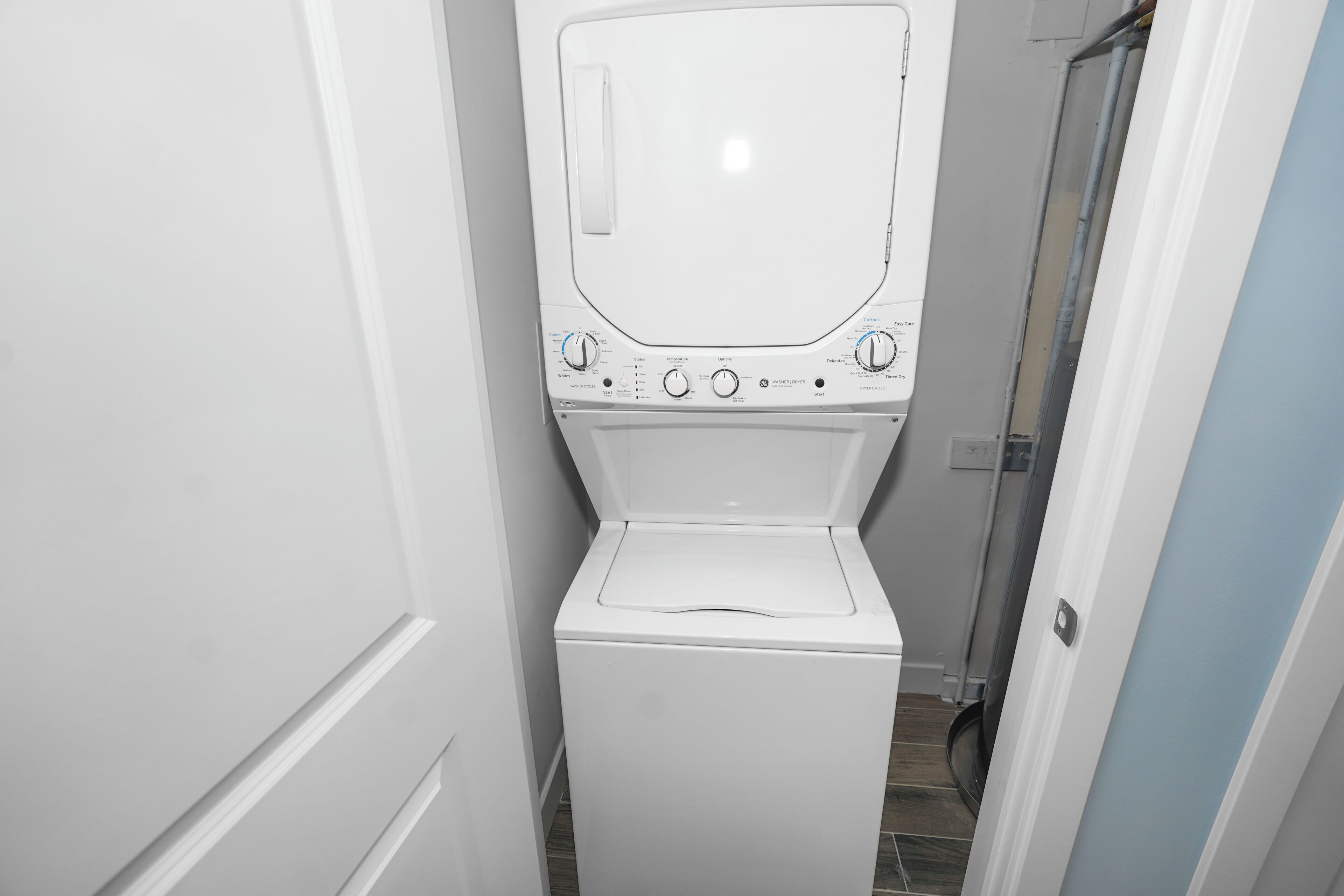 A compact, white laundry room with a front-loading washing machine, a dryer, and a small window.