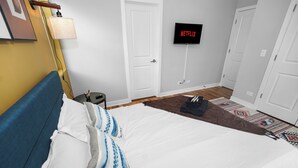 A bedroom with a bed, a TV mounted on the wall, a lamp, and a door. - Urban Chicago 3BR Retreat, 5 min to West Loop (Chicago)