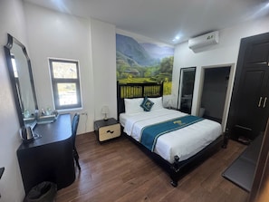 A bedroom with a bed, a dresser, a mirror, a window, a wall-mounted air conditioner, and a door. - Son Tinh Hotel (Dong Van)