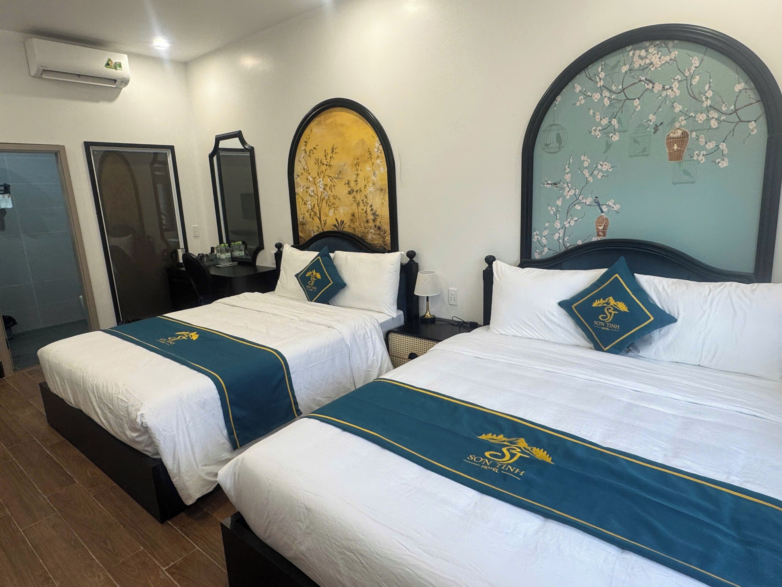 Une chambre d’hôtel avec deux lits, un grand miroir, une horloge murale et un élément décoratif fixé au mur.