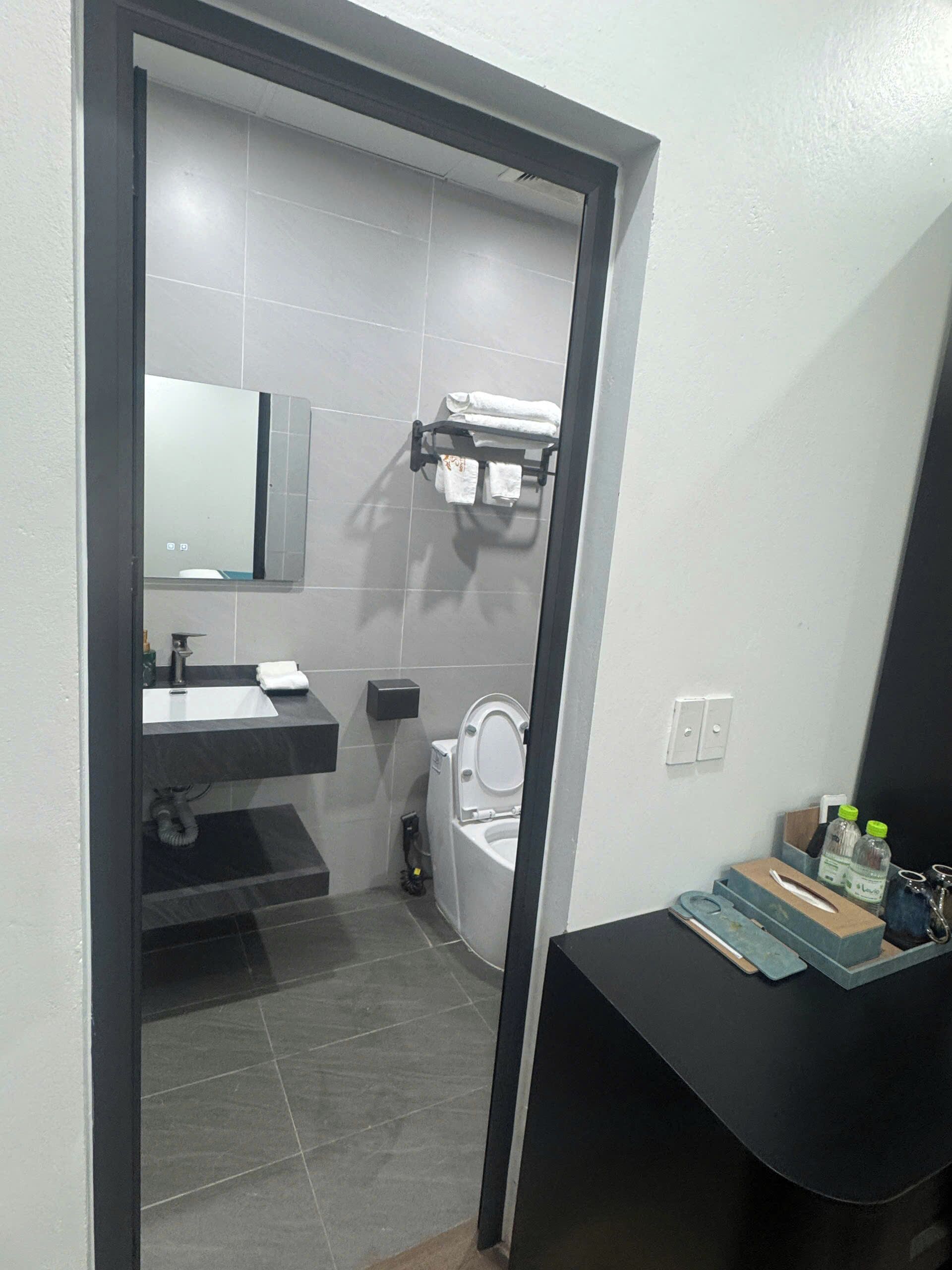 A bathroom with a toilet, sink, mirror, and towel rack.