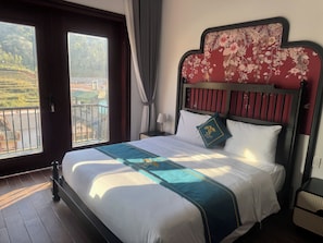 A hotel room with a bed, a nightstand, a lamp, a window with a view of a landscape, and a balcony. - Son Tinh Hotel (Dong Van)