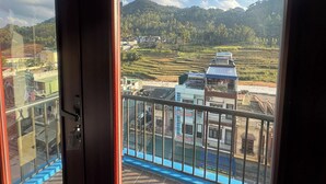 Un balcón con vistas a campos escalonados y una colina distante.